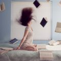 donna in ginocchio sul letto circondata da libri