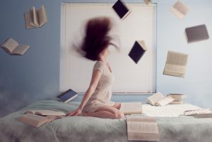 donna in ginocchio sul letto circondata da libri