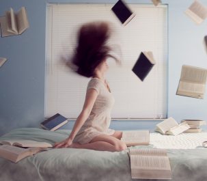 donna in ginocchio sul letto circondata da libri