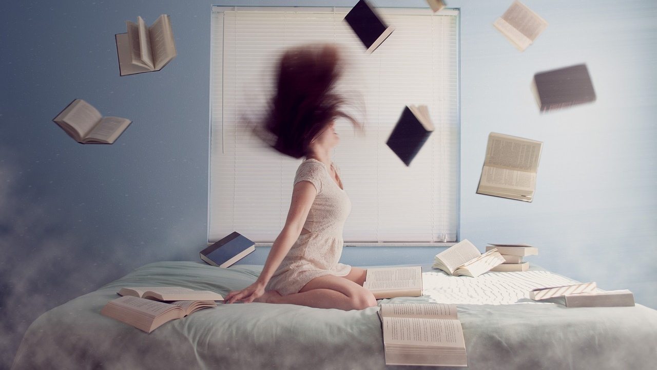 donna in ginocchio sul letto circondata da libri