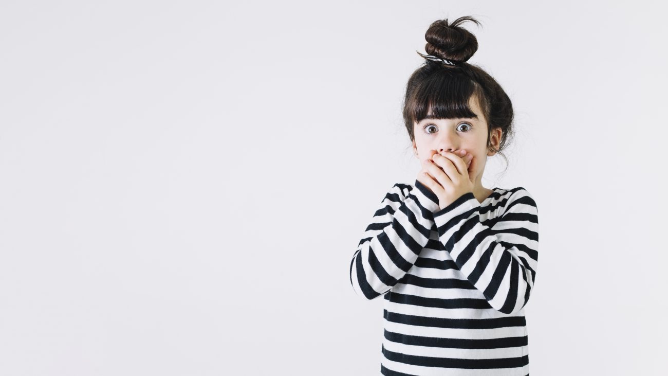 bambina sorpresa con mani davanti alla bocca