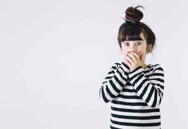 bambina sorpresa con mani davanti alla bocca